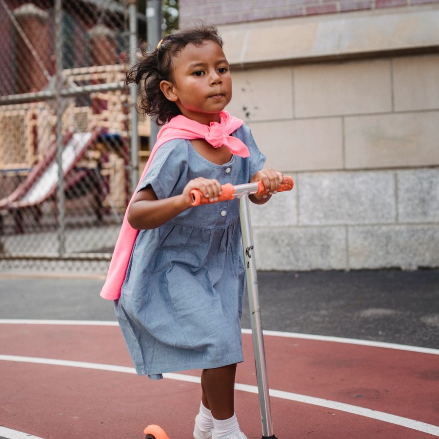 Une enfant fait de la trottinette dans la cour.
