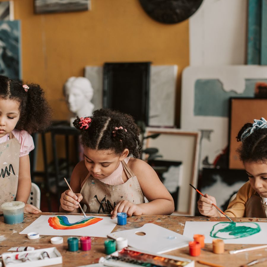 Des enfants peignent des arcs-en-ciel autour d'une table.