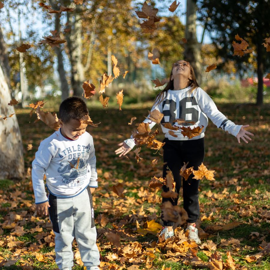 Des enfants jouent dans les feuilles d'automne au parc.