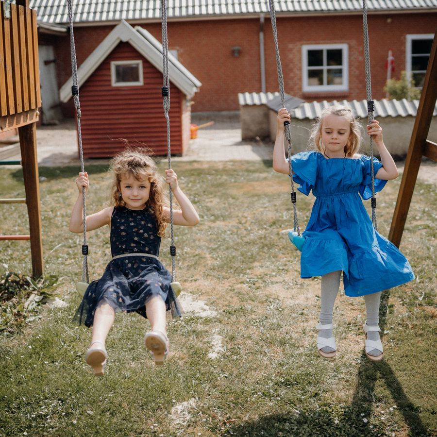 Deux enfants sur des balançoires dans le jardin.